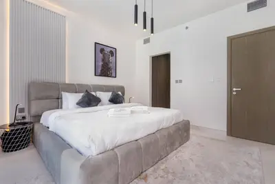 King bedroom with grey upholstered headboard and pendant lighting