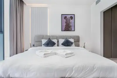 Close view of the white-linen king bed with dark blue accent pillows