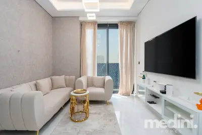 Living room with cream curved sofa, gold side table and large flat-screen TV