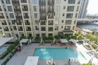 Aerial view of outdoor pool below with waterway and residential blocks beyond