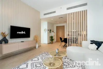 Living room with wall-mounted TV, white curved sofa, and slatted wood divider