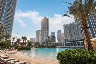 Outdoor lagoon-style pool area with palm trees and Dubai Creek Harbour towers