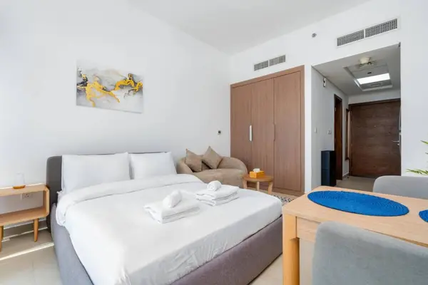 Studio with a double bed, sofa, wooden wardrobe, and a dining table for two