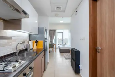 Galley kitchen with dark granite counter, gas hob, fridge, and hallway view