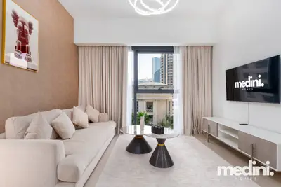 Living room with a beige sofa, two cone-base tables, TV, and city window