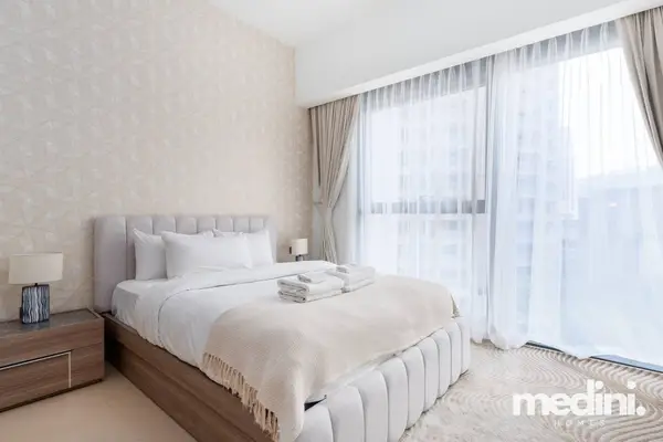 Bedroom with a double bed, textured wallpaper, and sheer curtains on a large window