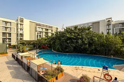 Outdoor pool surrounded by mature trees and residential building wings