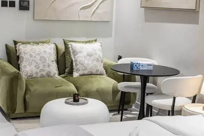 Green velvet sofa with patterned cushions next to a round dining table and white chairs