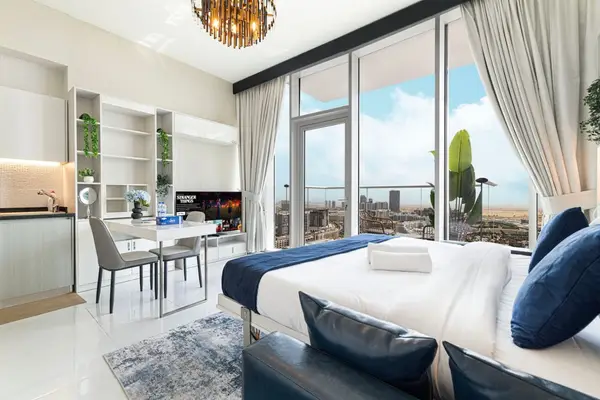 Studio with blue velvet bed, dining table and floor-to-ceiling city view windows