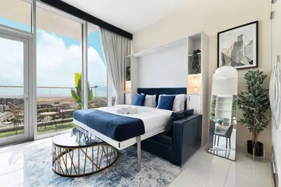 Studio from a different angle showing blue bed, living corner and balcony beyond