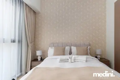 Bedroom with patterned wallpaper, white bedding, folded towels, and bedside lamps
