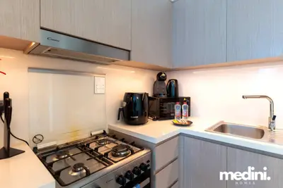 Kitchen counter with gas hob, coffee machine, kettle, and under-cabinet lighting