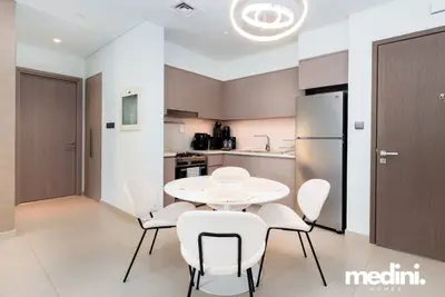 Open kitchen and dining area with round white table and stainless steel appliances