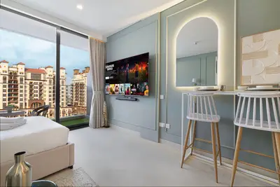 Studio corner showing wall-mounted TV, arched mirror, and bar-height desk