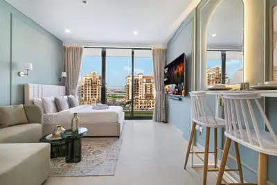 Open studio space with floor-to-ceiling windows, sofa, and wall-mounted TV
