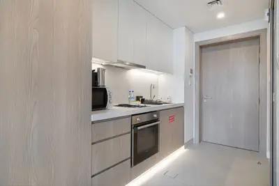 Compact kitchen with built-in oven, hob, and light wood cabinetry