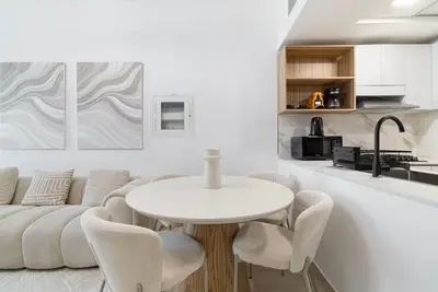 Dining area with round wooden table and four chairs next to the open kitchen