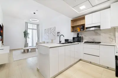 L-shaped kitchen with white cabinets, marble backsplash, and island counter