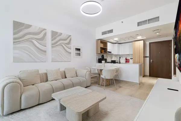 Open-plan living room with cream sofa, coffee table, and kitchen in background