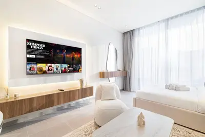 Studio with wall-mounted TV, floating wood console, and bed near large window