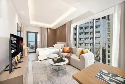 Bright studio with sofa, floor-to-ceiling windows, and a view of adjacent towers