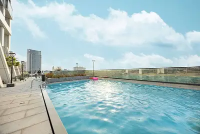 Rooftop pool with blue water, a pink float, and skyline in the background