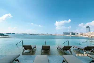 Long row of sun loungers on the pool deck beside residential towers