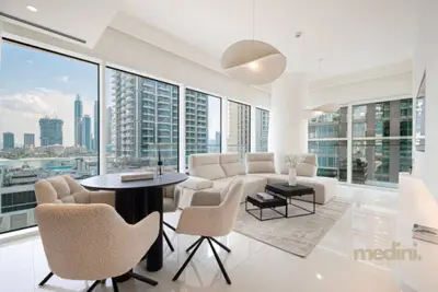 Open living and dining area with a sofa, round table and floor-to-ceiling windows