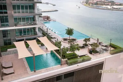 Aerial view of the outdoor pool deck with shade sails and a sea inlet beyond