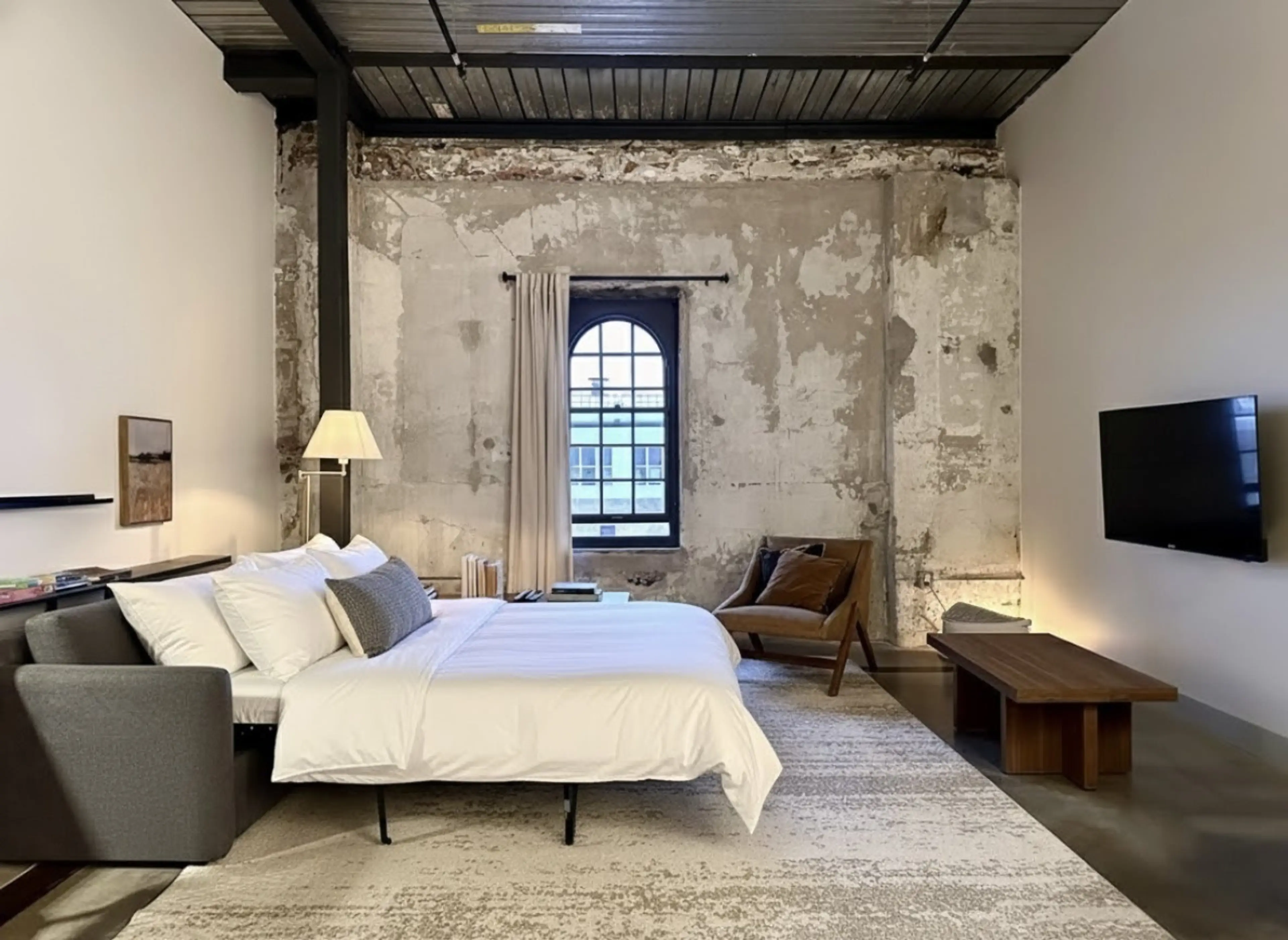 Spacious living room with charming brick features, a sofa bed, dedicated workspace, and dining table