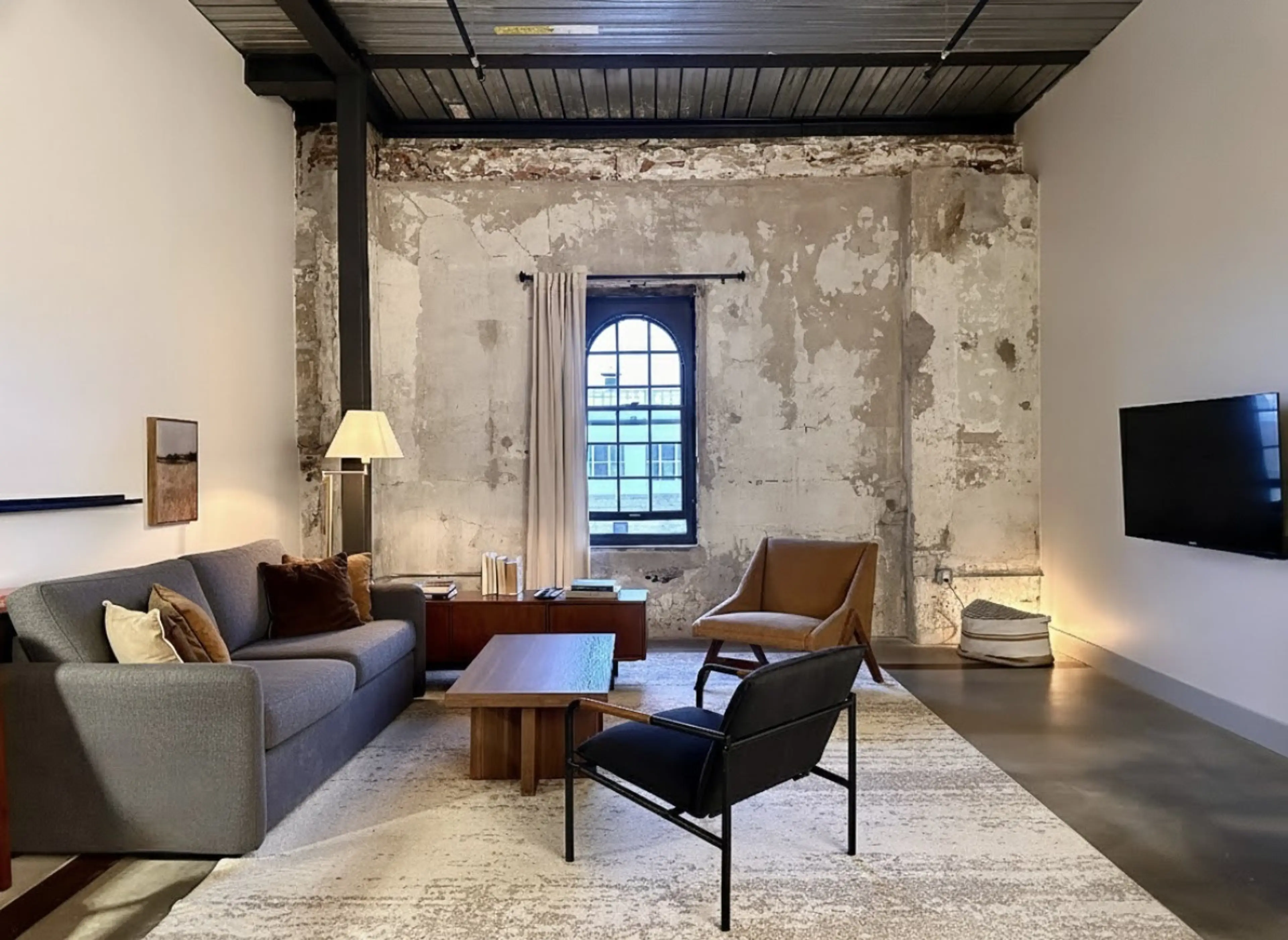 Spacious living room with charming brick features, a sofa bed, dedicated workspace, and dining table