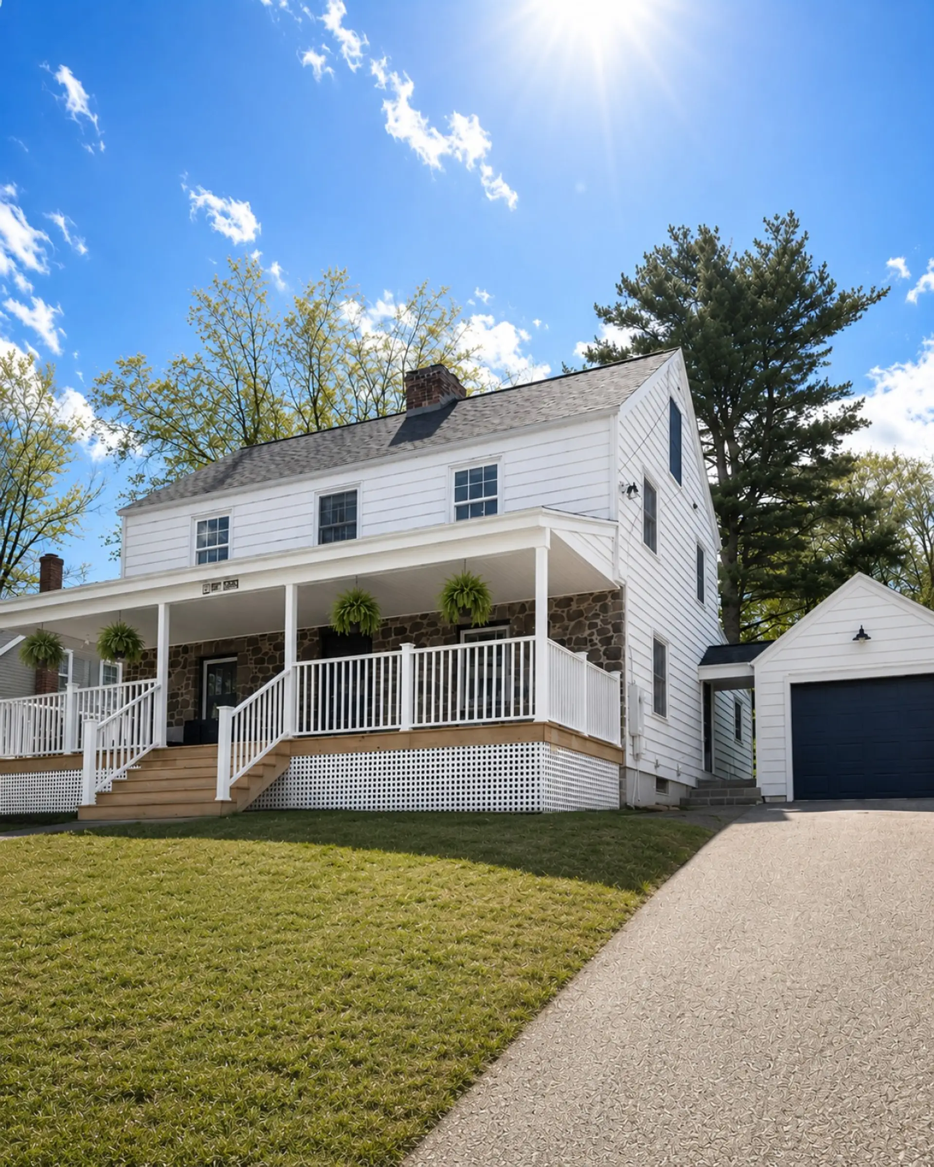 Classic New England charm with original stonework, a spacious covered front porch, and a welcoming lawn surrounded by mature trees.