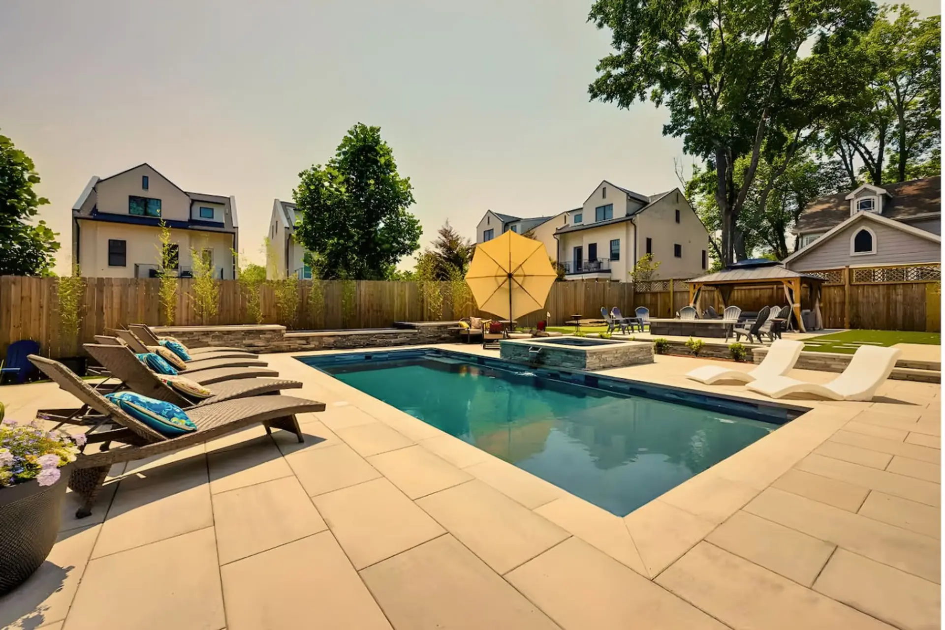 Swimming pool with lounge chairs and patio area surrounded by a wooden fence