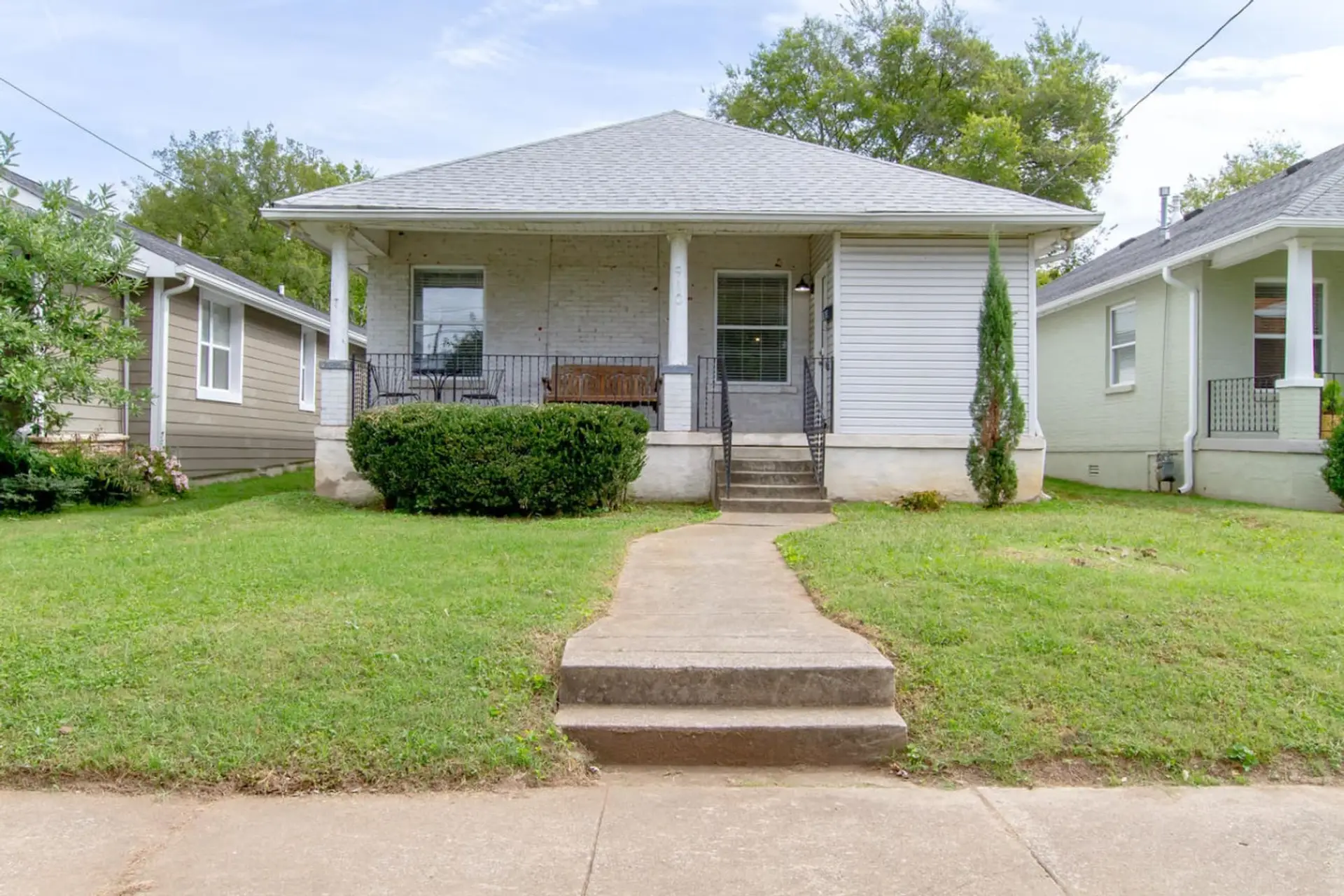 Inviting craftsman-style facade with a cozy porch and leafy surroundings.