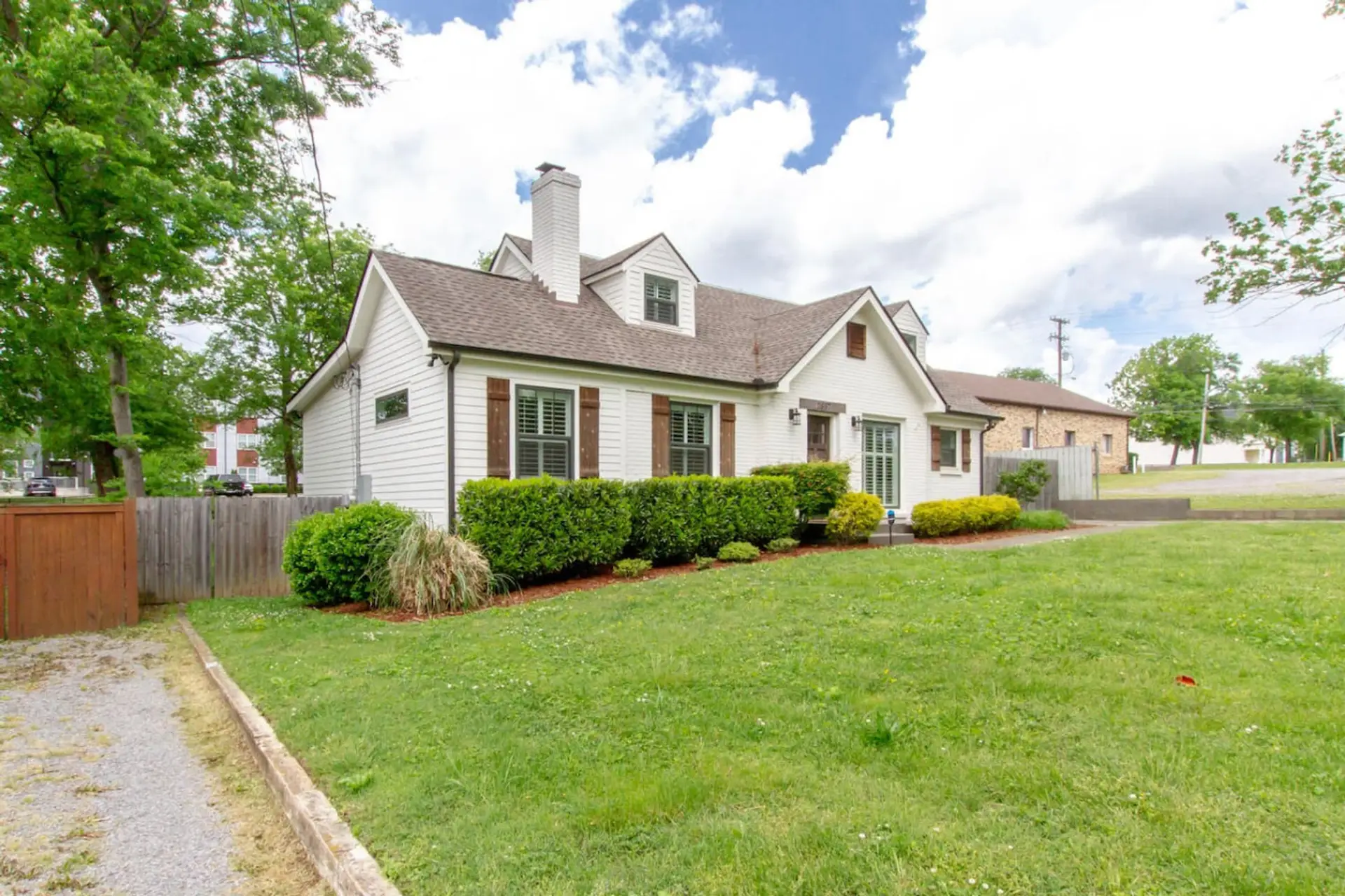 Charming white cottage exterior with classic dormers and a beautifully landscaped front yard