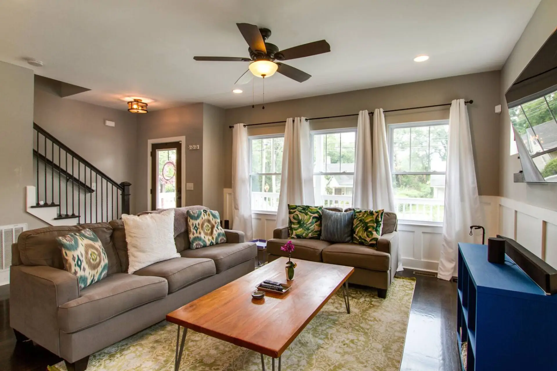 Living room with a gray sofa, coffee table, ceiling fan, and large windows