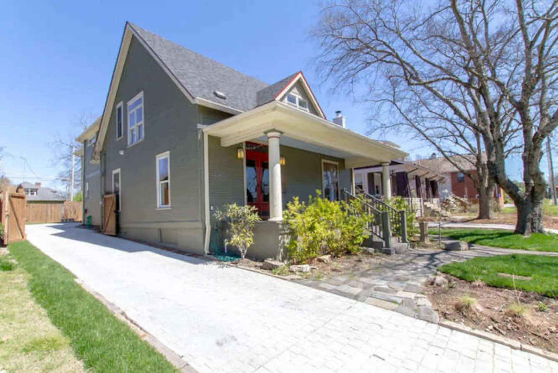 Exterior of classic craftsman-style home with front porch, gray exterior, and winter bare trees