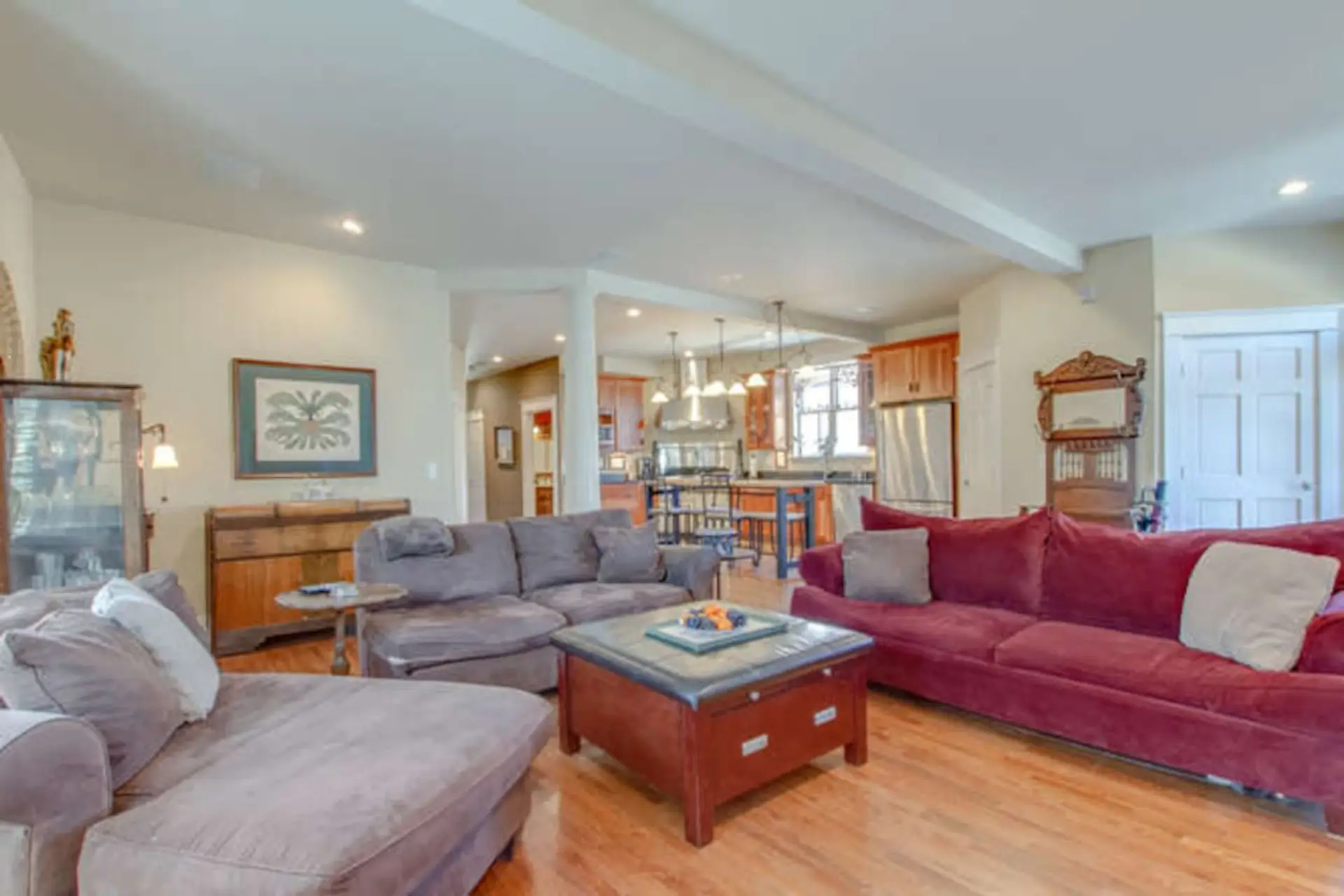 Living room with gray sofa, red/burgundy accent chairs, warm lighting, and hardwood floors