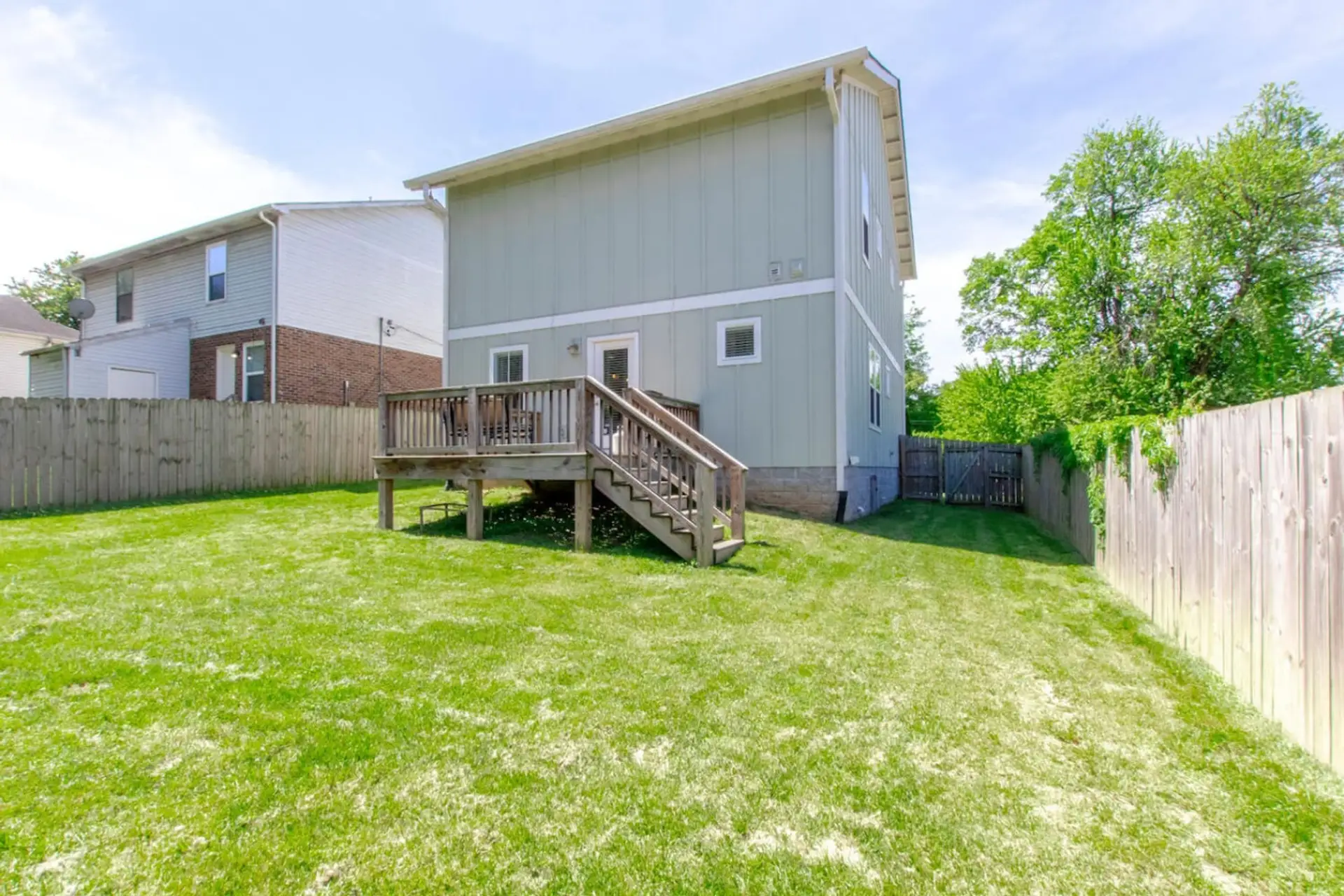 The generous backyard with a wood deck and lush green lawn is perfect for outdoor gatherings.