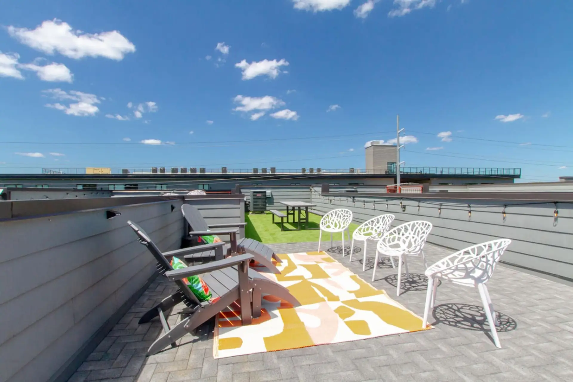 Rooftop patio with Adirondack chairs and a colorful rug — perfect for soaking up the sun