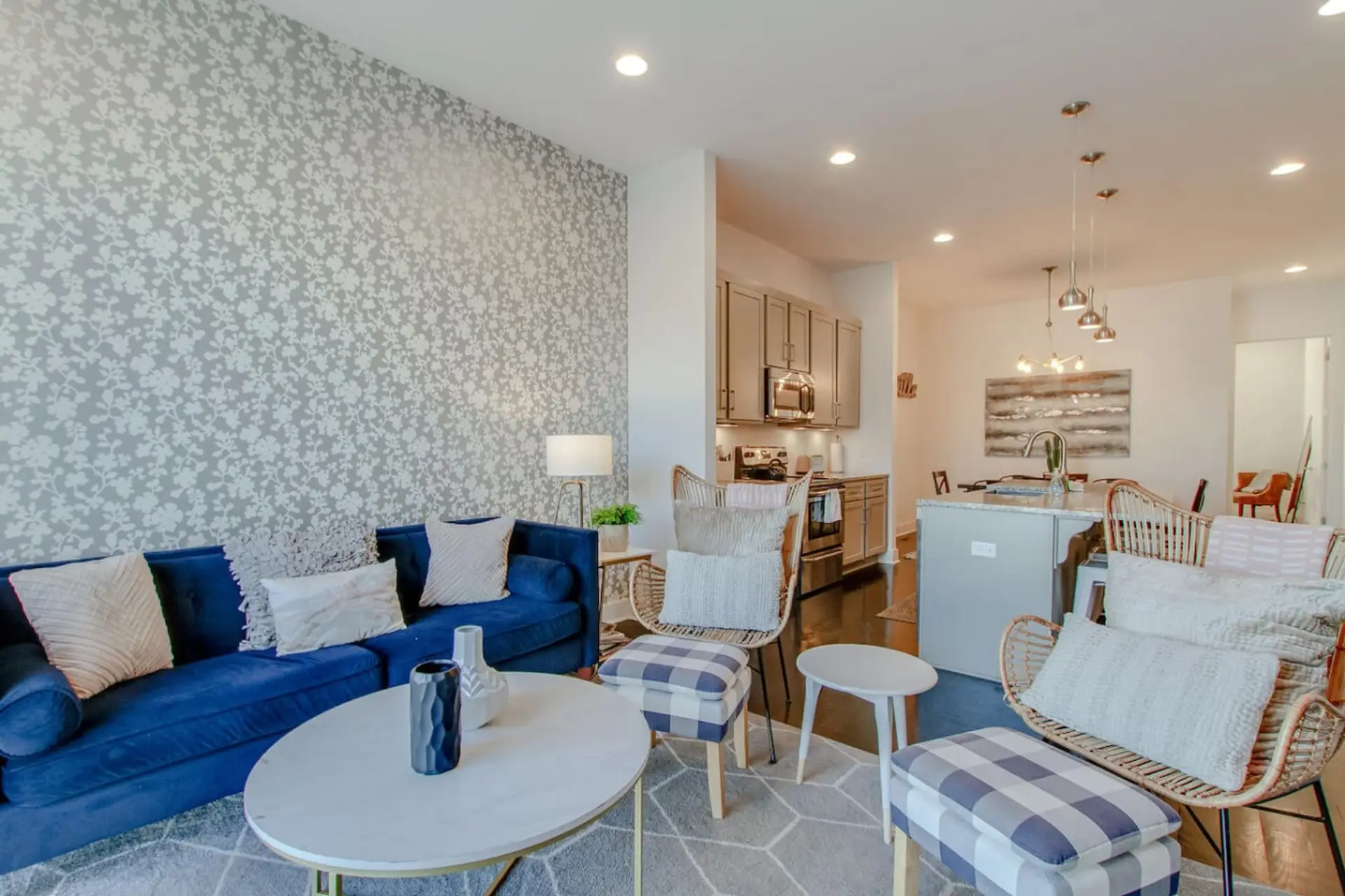 An open and airy living area with a plush blue couch, white accents, and a flowing layout into the dining space.