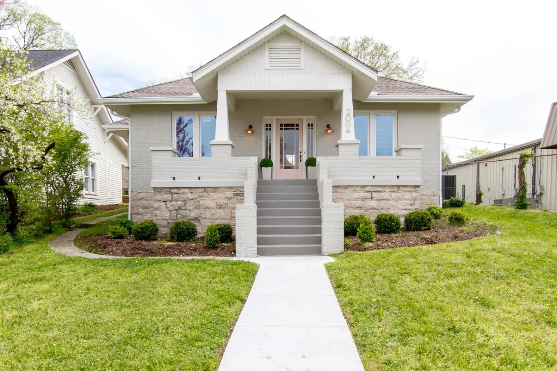 Exterior front of craftsman-style home with stone facade, green lawn, and front steps