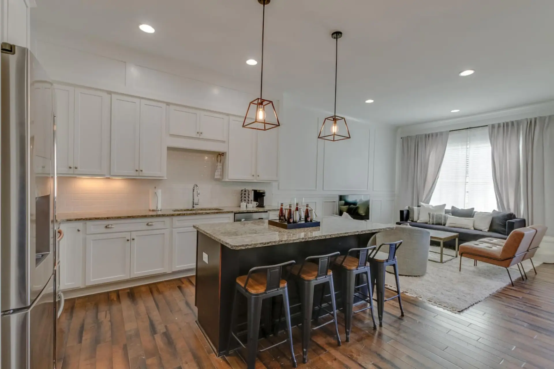 The open kitchen with white cabinetry, a marble island, and pendant lighting is perfect for entertaining.