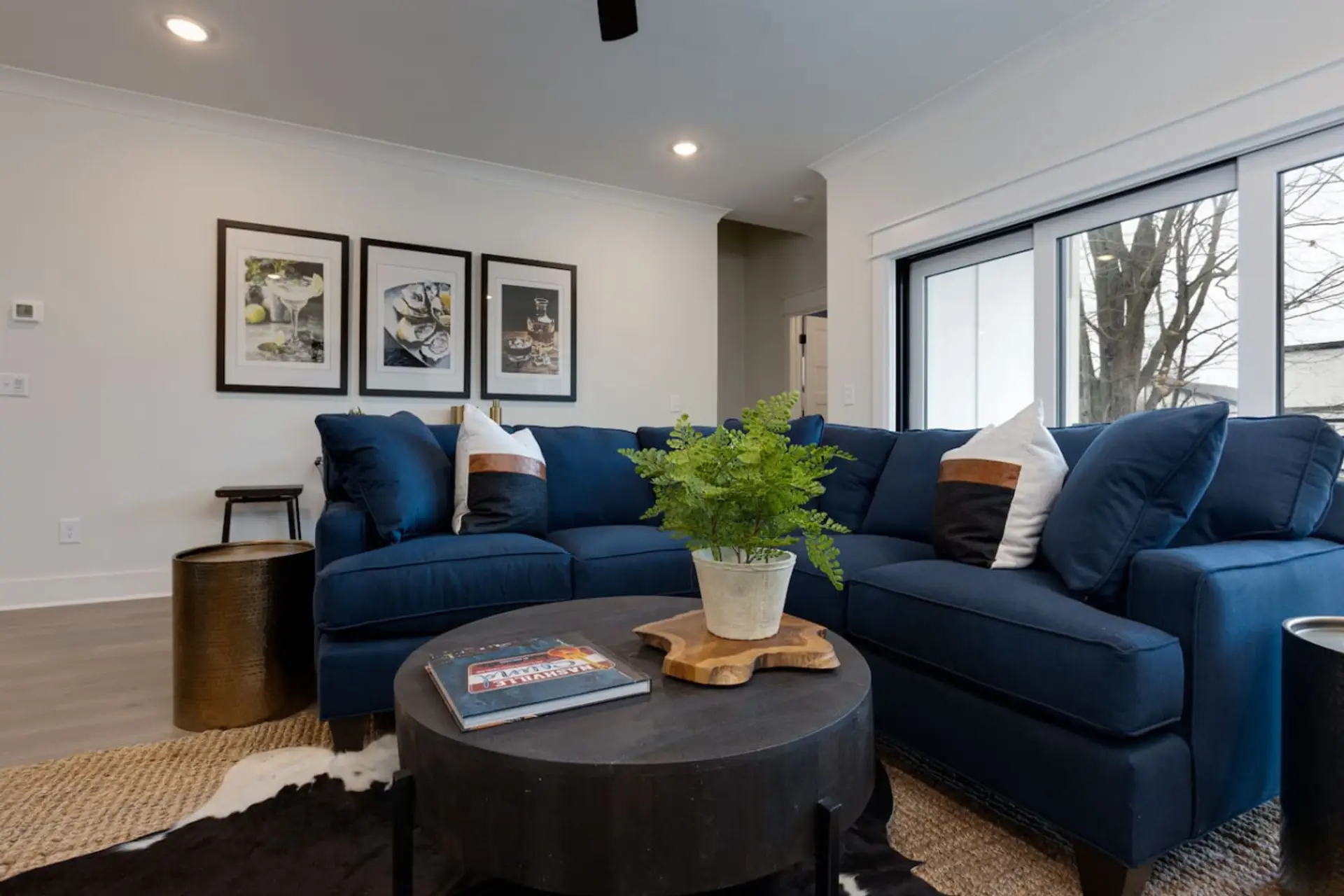 Living room with navy blue sectional sofa, gallery wall art, and large windows