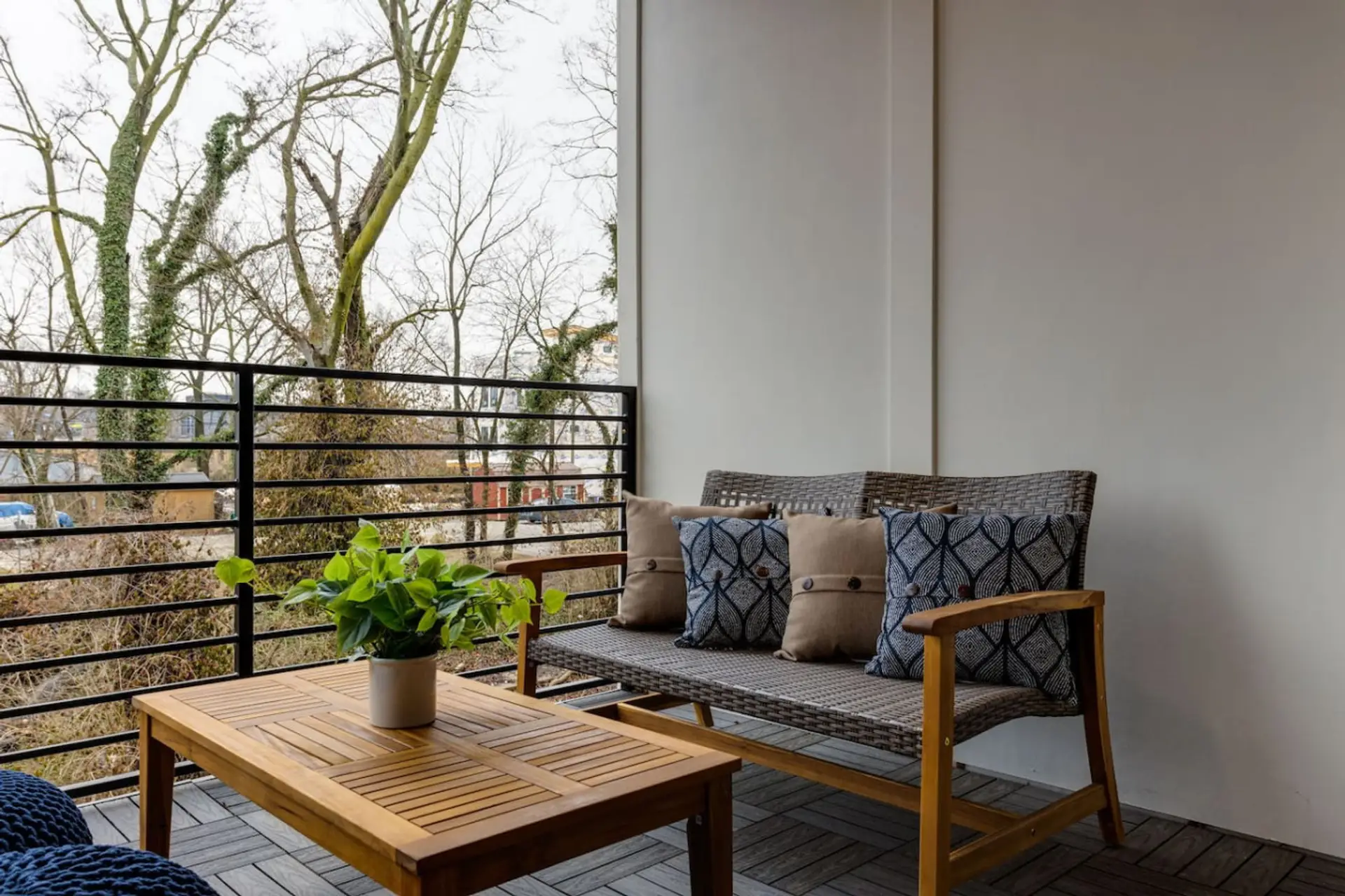 Balcony with outdoor teak table and chairs, plant, and iron railing