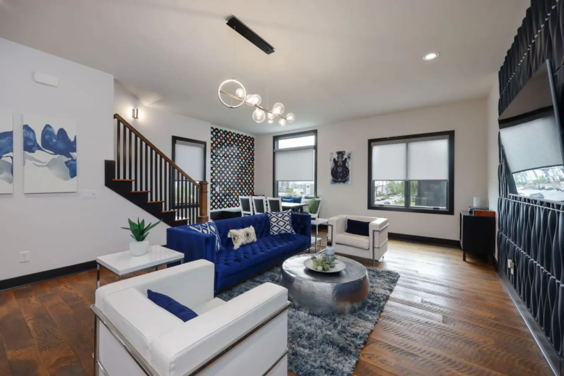 The elegant living room features a blue velvet couch, bold decor, and a music-forward Nashville aesthetic.