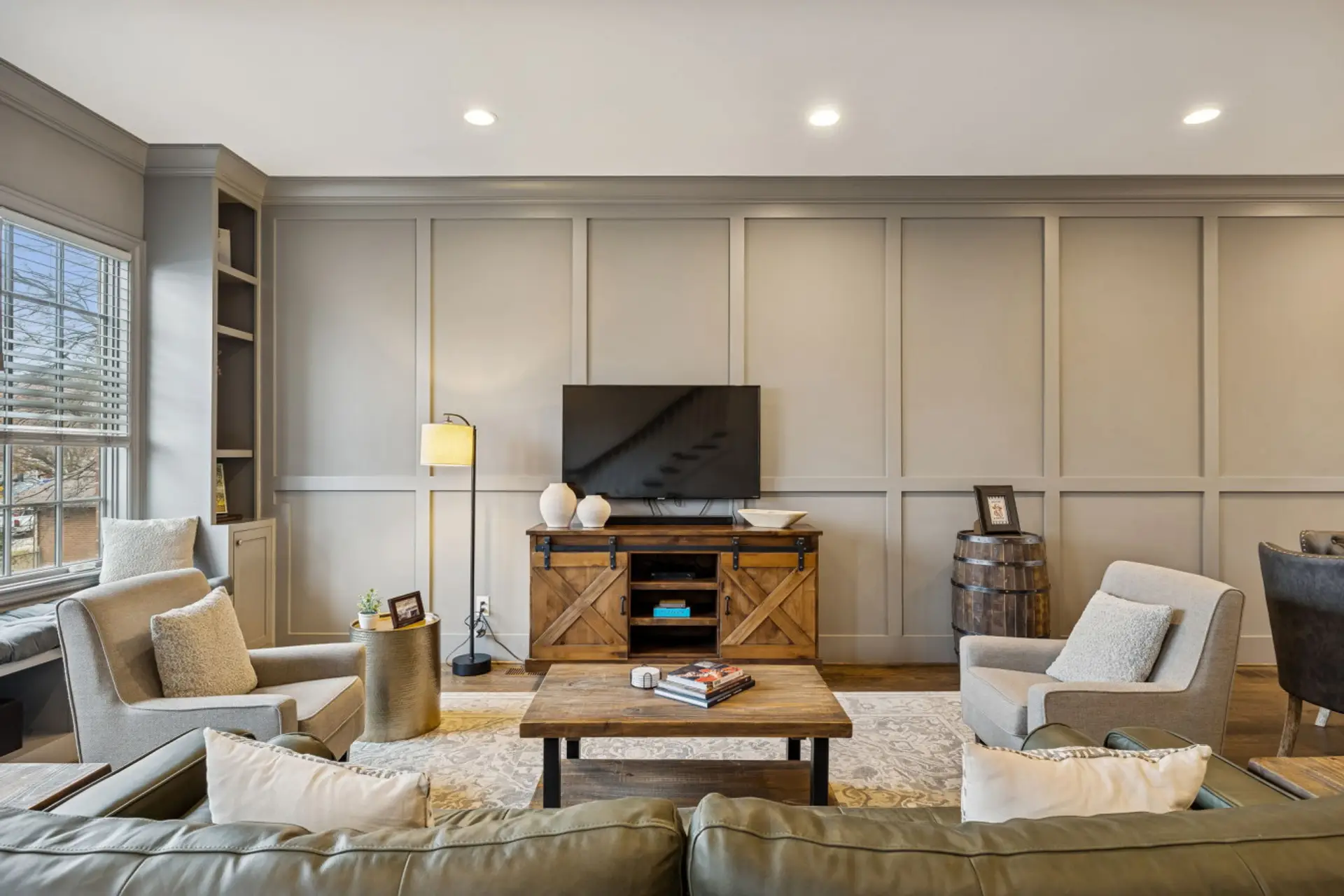 A stylish living room with a wainscoting accent wall, leather chair, and flat-screen TV creates an inviting retreat.