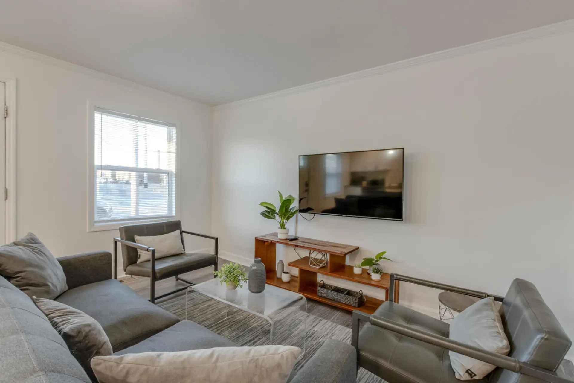 Living room with a gray sofa, TV on console table, and accent chairs