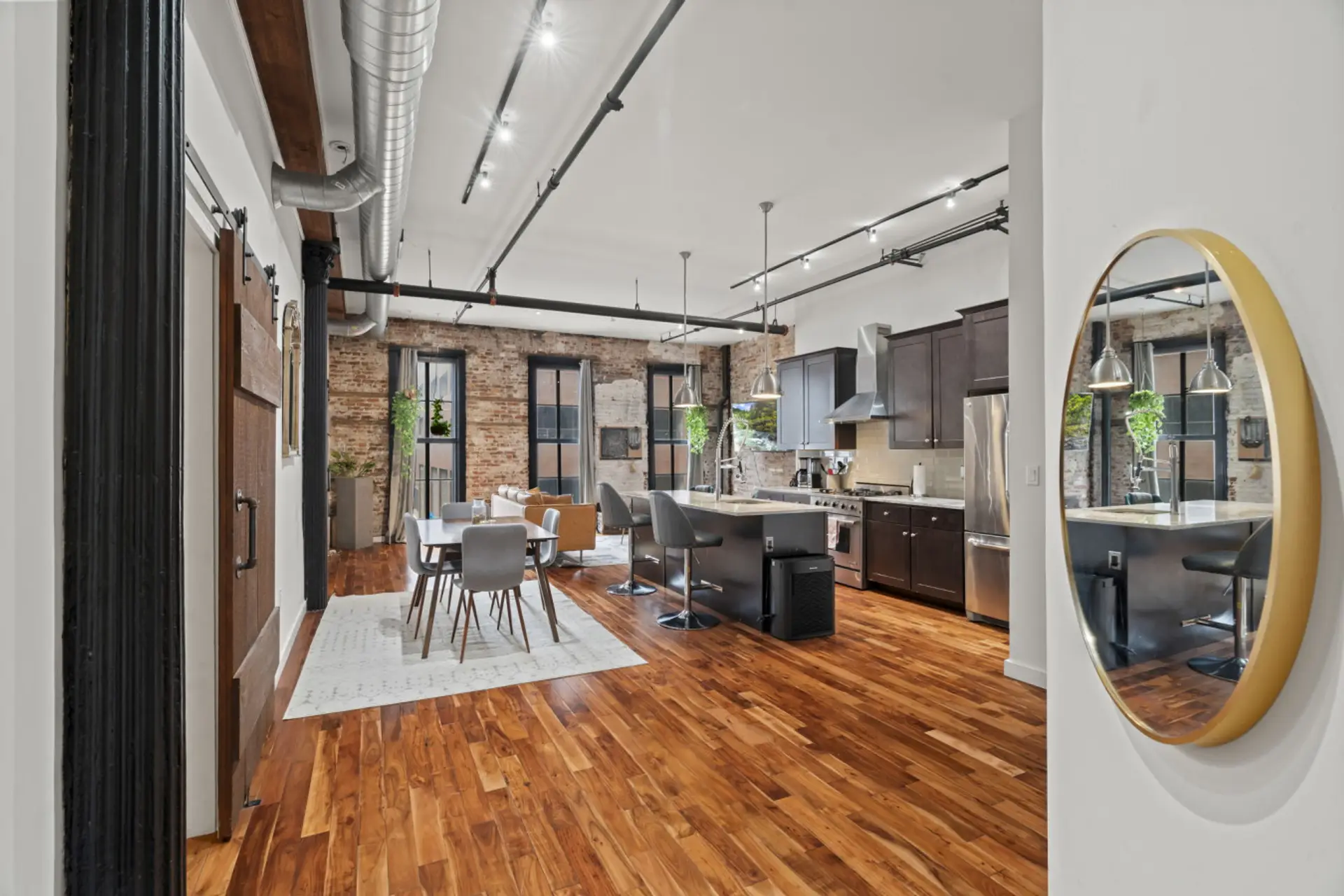 Bright, industrial-style living room with exposed brick, modern furnishings, and a brand-new smart TV.