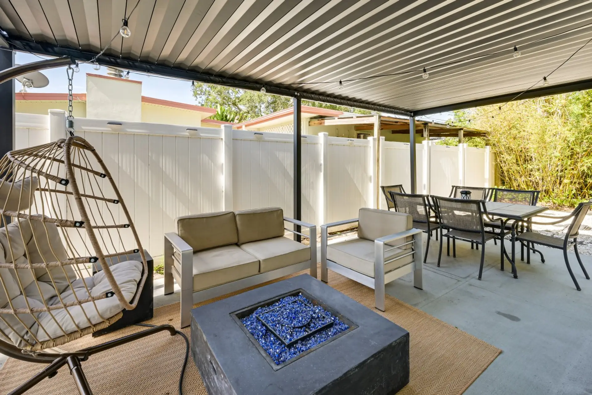 Patio with swinging egg chair, fire pit, sitting area and additional outdoor dining.
